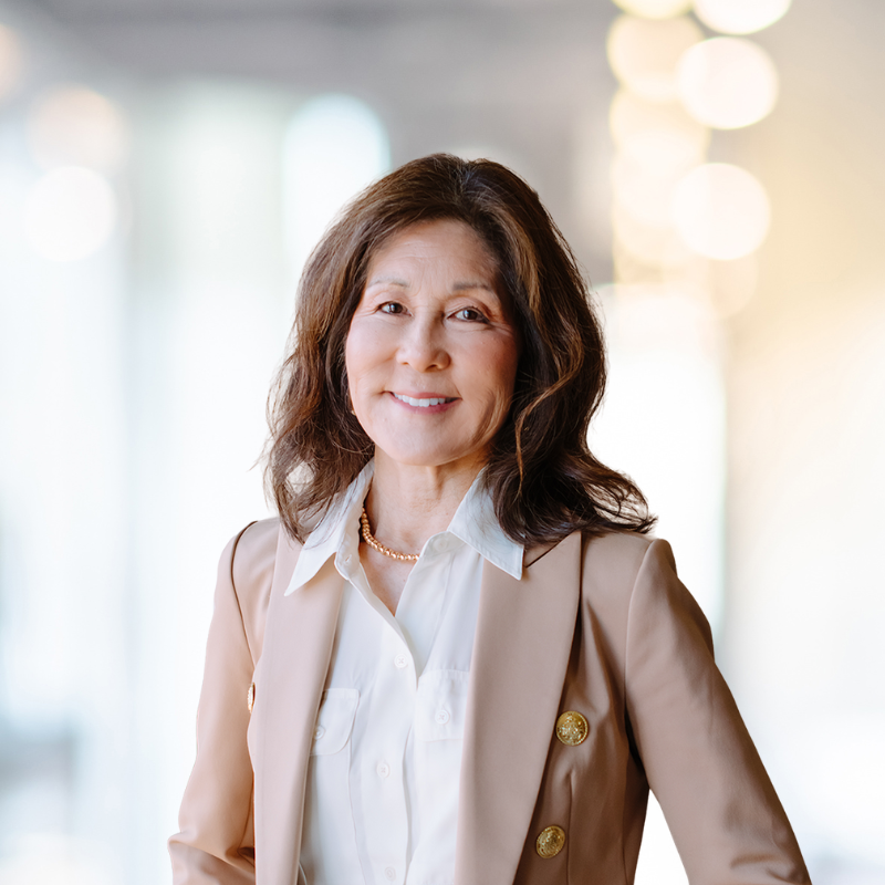 Densie staring into the camera, wearing a tan jacket.